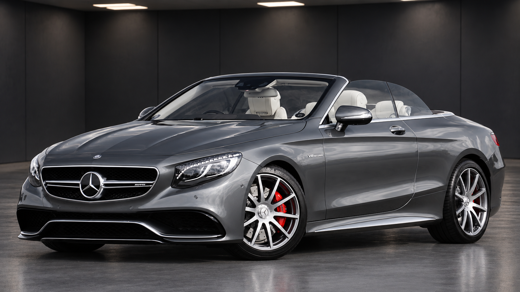 Grå Mercedes-Benz cabriolet i ett mörkt showroom, med hela bilen synlig
